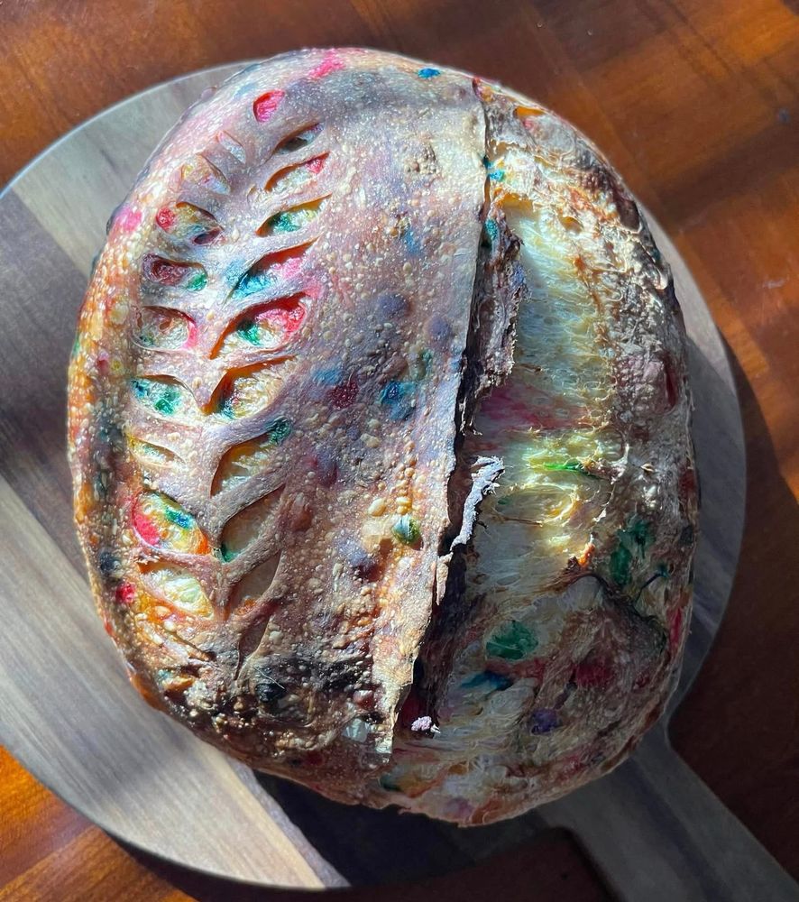 rainbow funfetti sourdough bread loaf on a wood board