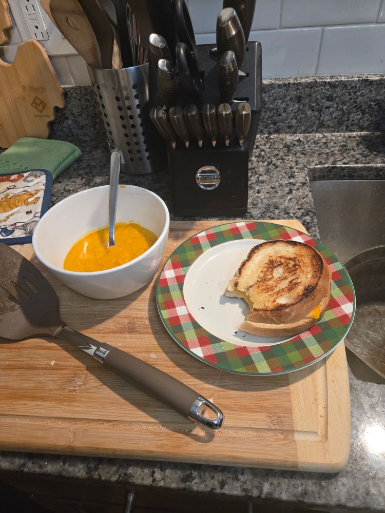 A bowl of vegtable soup and grilled cheese
