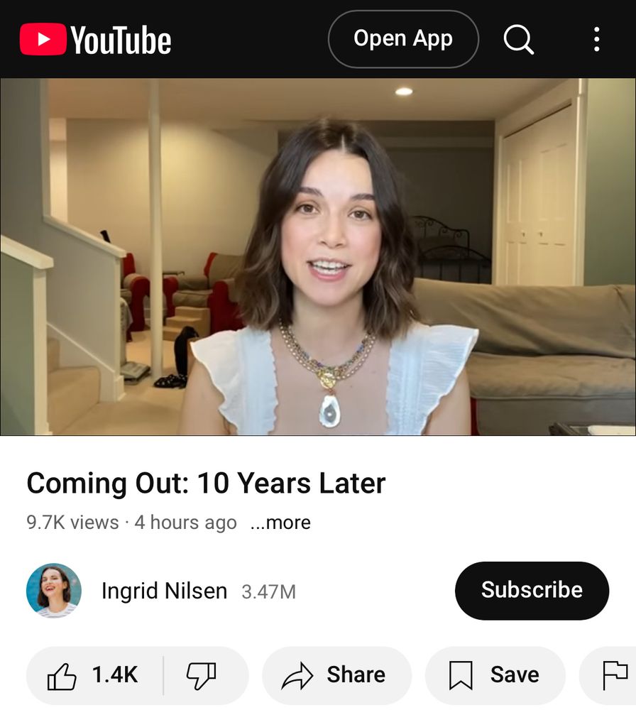 Screenshot of Ingrid nilsen’s YouTube channel. She’s sitting alone in front of the camera in a white top. The title of the video is “coming out: 10 years later.” 
