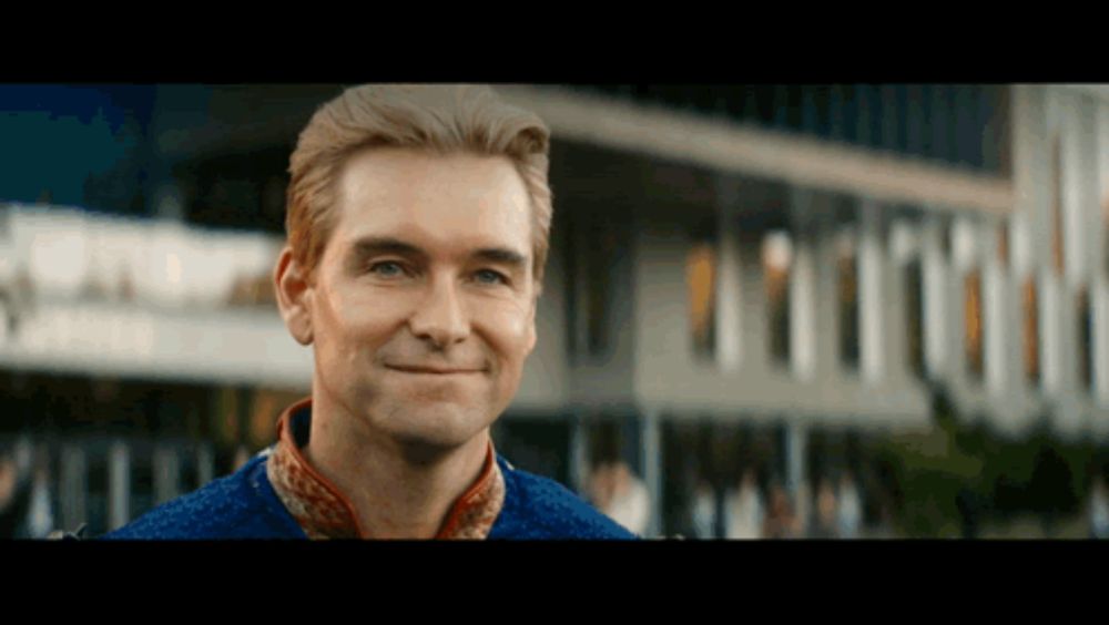 a man is smiling in front of a building with a sign that says ' a ' on it