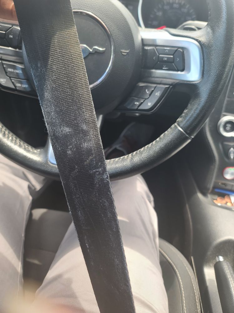 Lettering from a t shirt melted onto a seat belt aka an indication that it is HOT