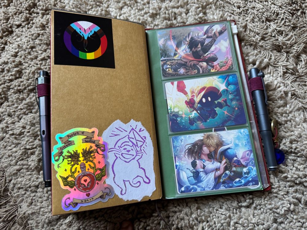 More stickers and MTG art cards in a plastic card holder on the inside of a traveler’s notebook