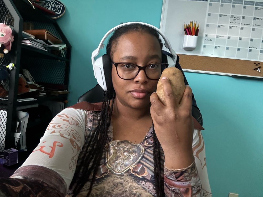 LaTia is dressed in a Holga costume from the D&D movie and holding a potato.