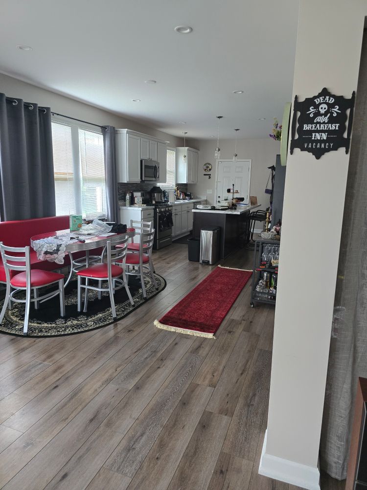 "Dead and Breakfast Inn" sign hanging on a column, a red and chrome diner set on a black oval-shaped rug, and a red runner rug leading to a kitchen
