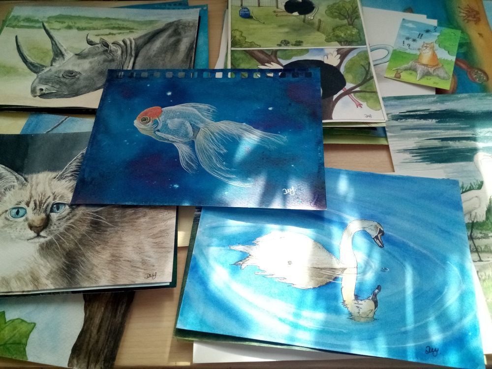 Photograph of a selection of original paintings stacked and arranged on a large wooden easel.