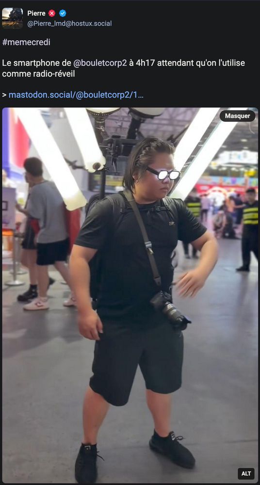 Image : Une personne est au milieu d'un hall, semblant pour une convention ; équipée d'un dispositif supportant plusieurs (trop ?) appareils d'éclairage de photographie ; ainsi qu'un appareil photo professionnel en bandoulière. Les verres de ses lunettes sont éclairées en blanc depuis le coté intérieur, lui donnant une intensité, façon anime. Sa main se porte vers sa caméra avec un flou de mouvement rapide

Texte de Pierre : Le smartphone de @bouletcorp2 à 4h17 attendant qu'on l'utilise comme radio-réveil