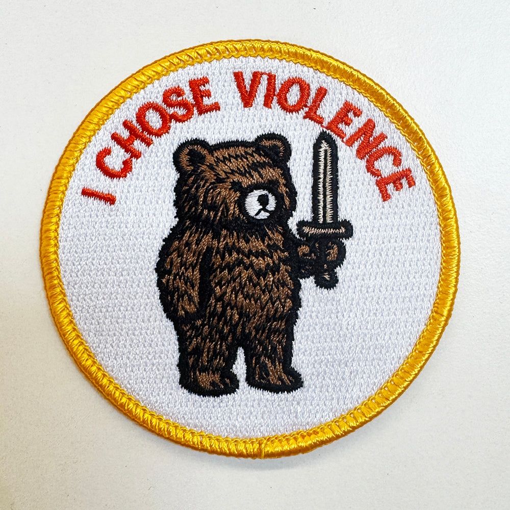 A round white patch of a bear holding a sword. It says "I chose violence".