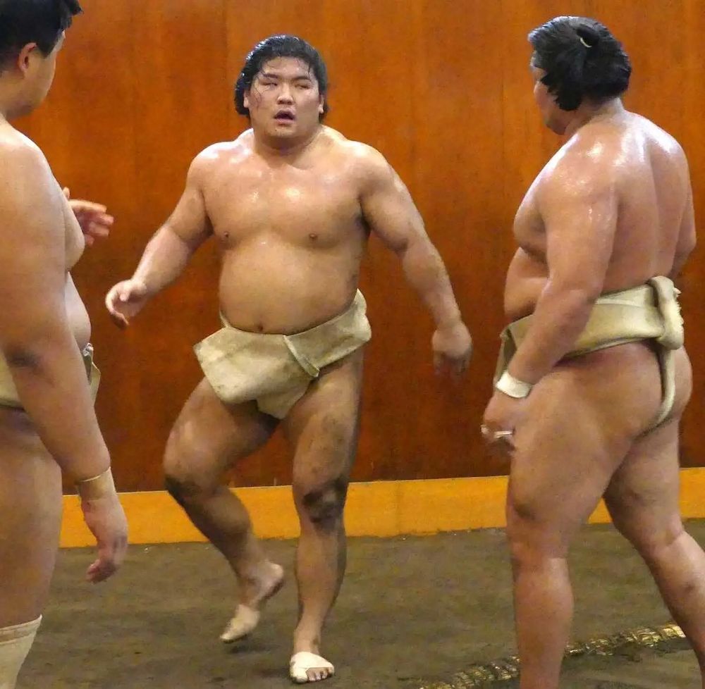 Takuma training at the stable with his fellow sumo, drenched in sweat and caked in mud from the ring.