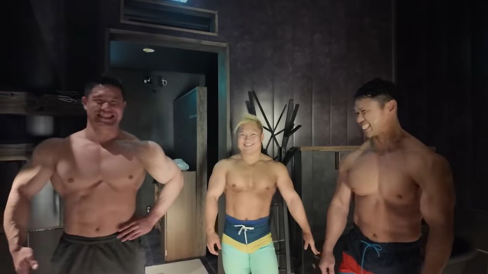 Three of the bodybuilders standing in the lobby. The one in the middle is notably shorter than his bulkier comrades.