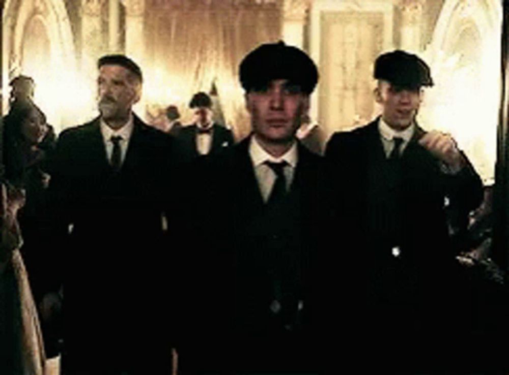 a group of men in suits and hats are walking through a hallway .