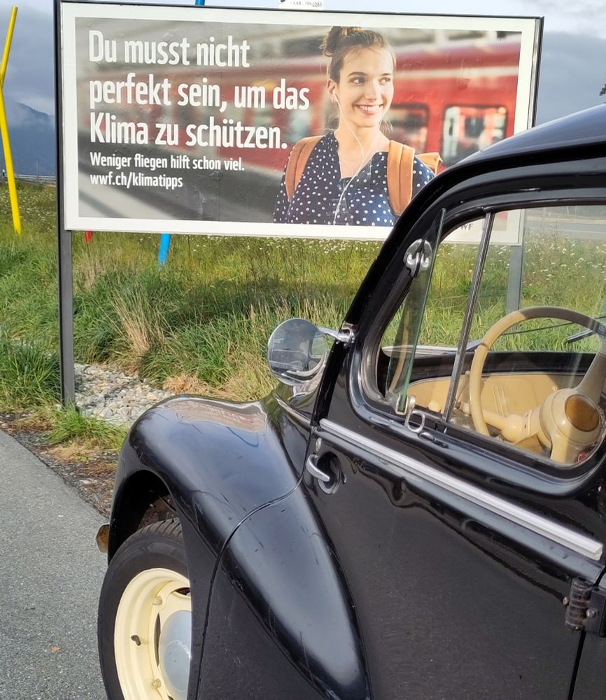 Plakat mit der Aufschrift "Du musst nicht perfekt sein, um das Klima zu schützen". Davor ein schwarzer Renault 4CV Oldtimer