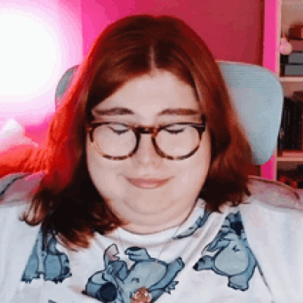 a woman wearing glasses and a stitch shirt smiles with her eyes closed