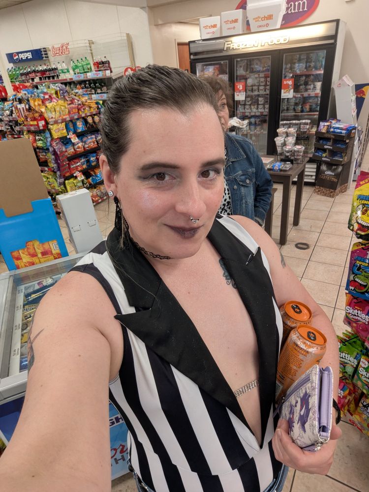 Me in a black and white striped body suit that's cut down to my belly button with a gem chain link in the middle and solid black collar. My hair is pulled back.