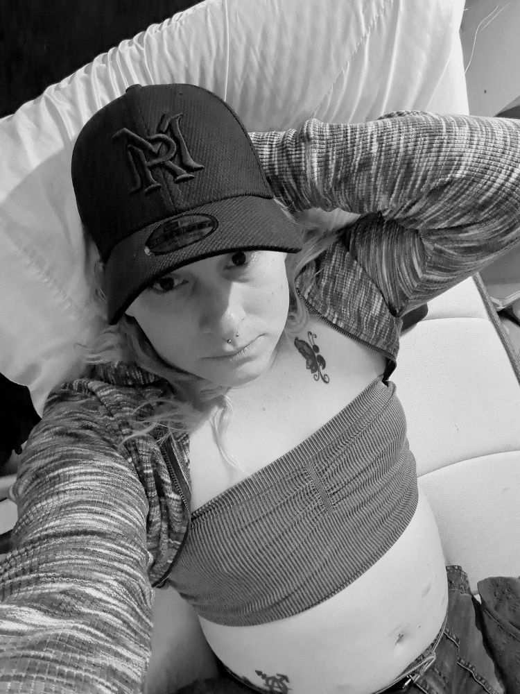 Me in a tube top and crop hoodie and my modern ritual hat on.  My Tranarchy and semicolon butterfly tattoos are visible.