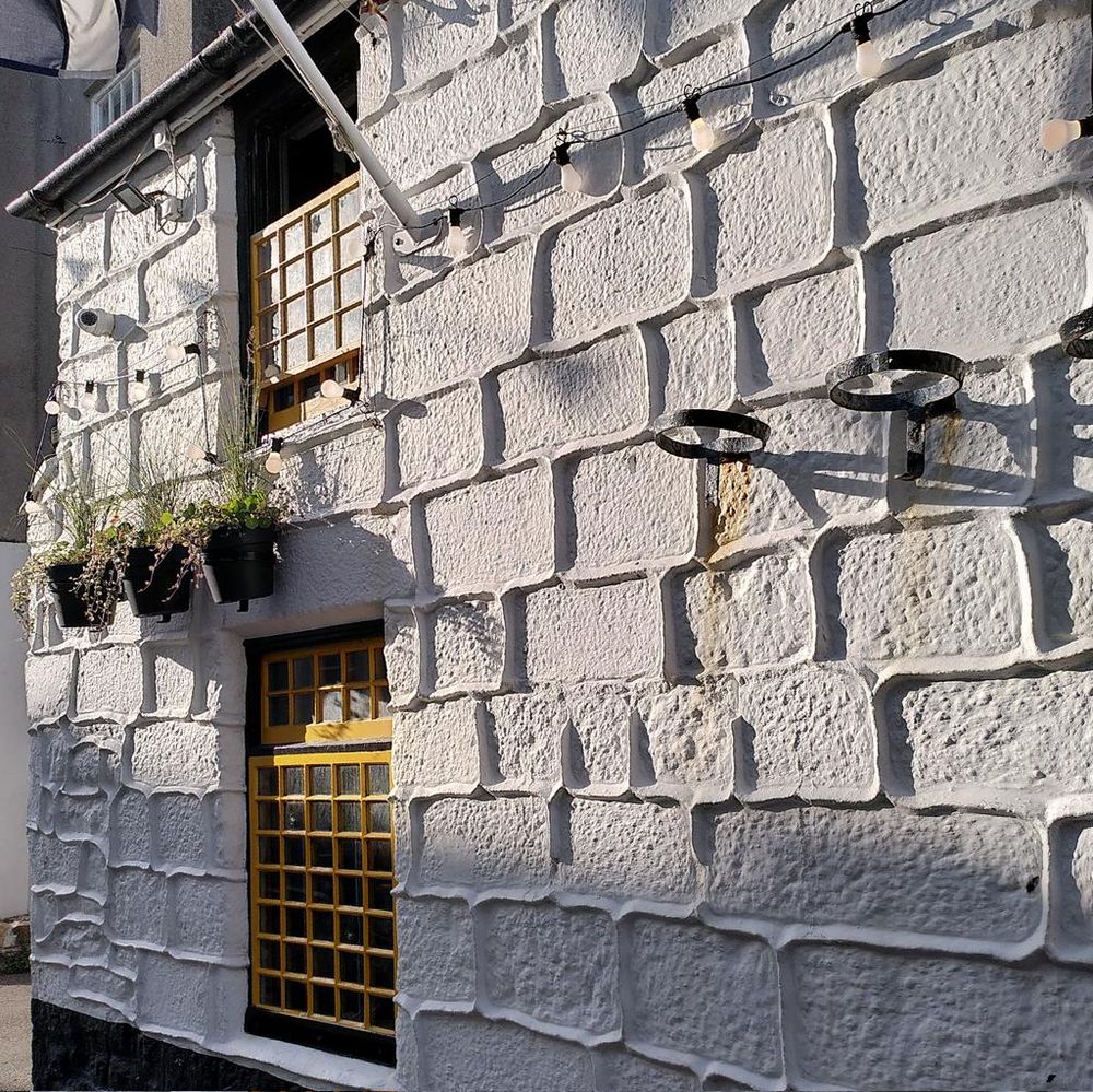 A whitewashed pub wall, with mortar standing proud of the stones.