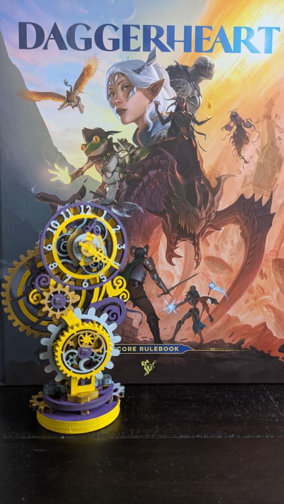 Daggerheart core rulebook in the background. Laser cut wood steampunk style clock painted in purple and yellow