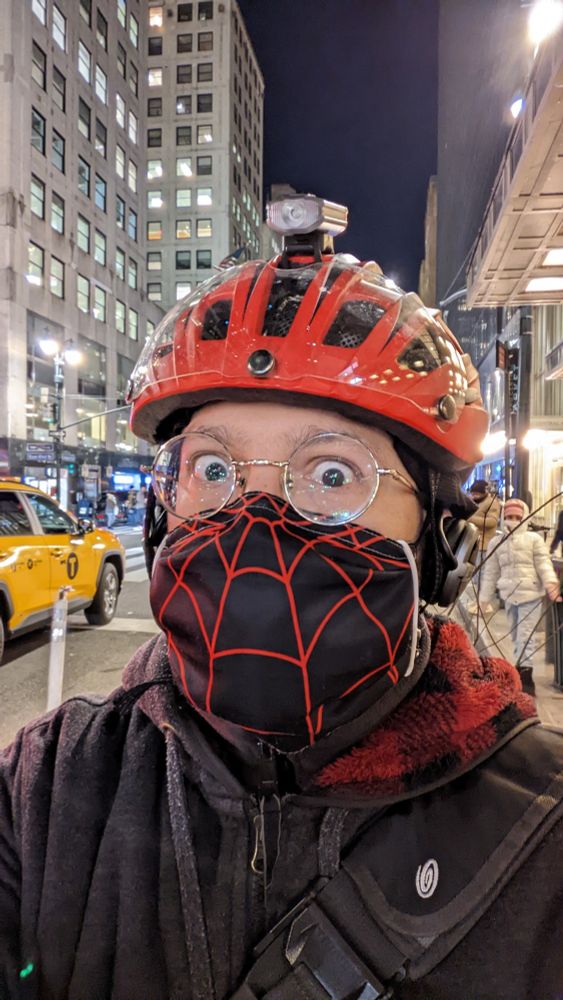 Me wearing a Miles Morales face mask, red bicycle helmet, and looking a little deranged per my usual.
