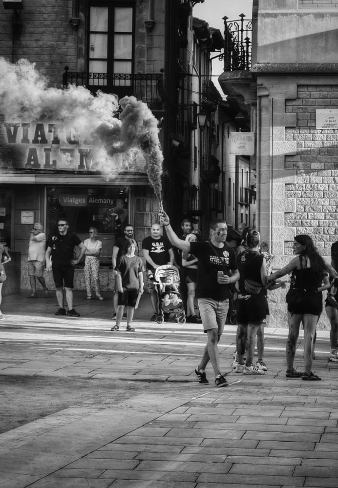 Un noi porta una bengala de fum per agrupar la seva colla a la plaça. Es la festa major de Vic. 