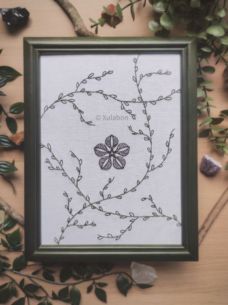 Broderie d'une fleur en métal attachée avec des feuilles brodées autour