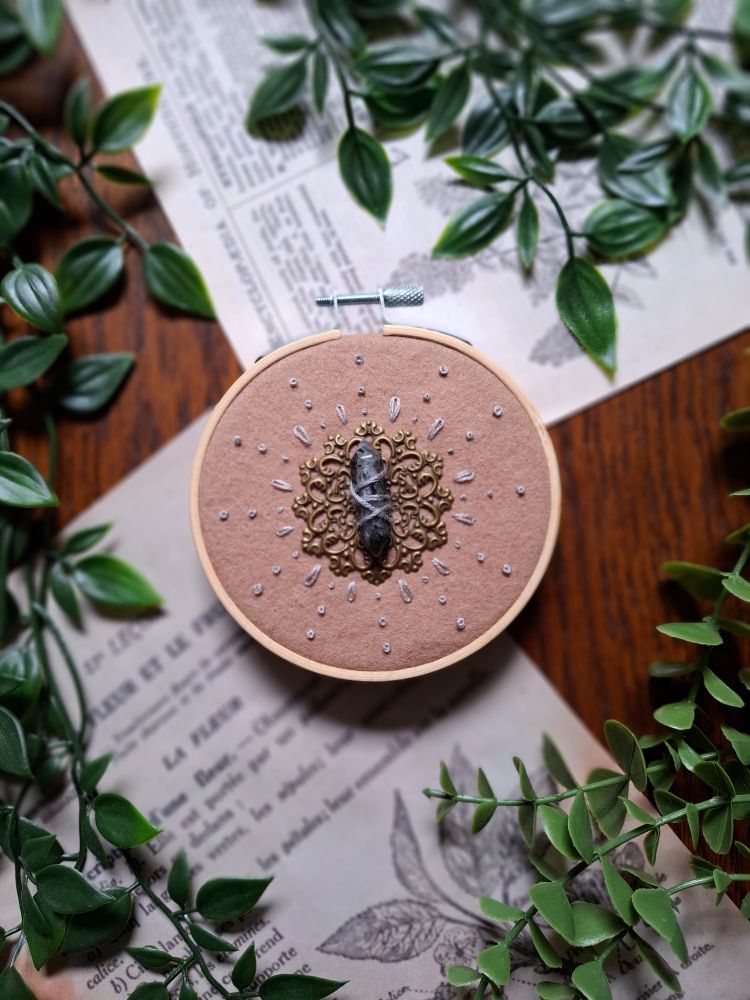 Broderie pierre grise attachée sur un ornement cuivré et d'autres ornements brodés autour