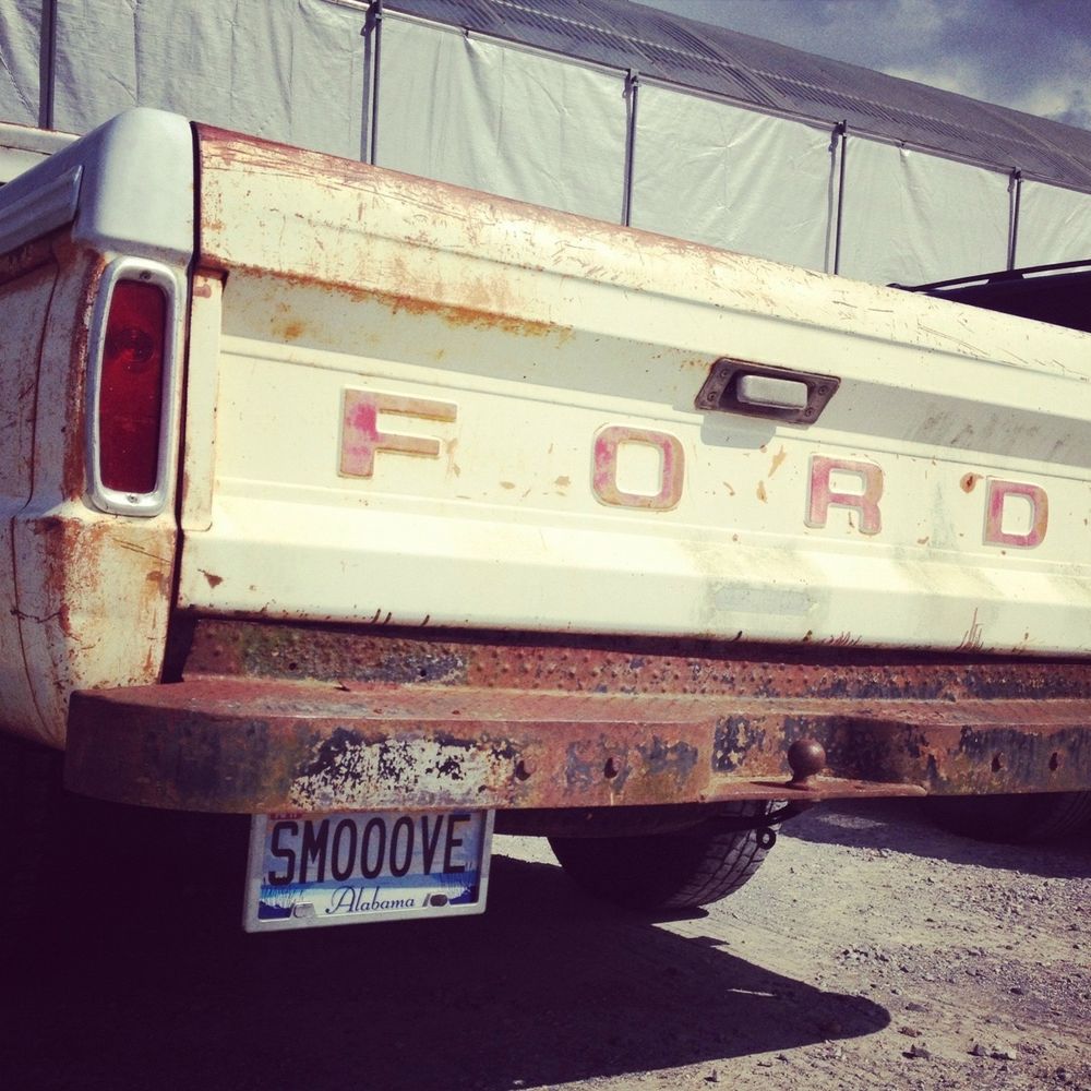 back end of a white ford pickup with a vanity Alabama plate that says SMOOOVE