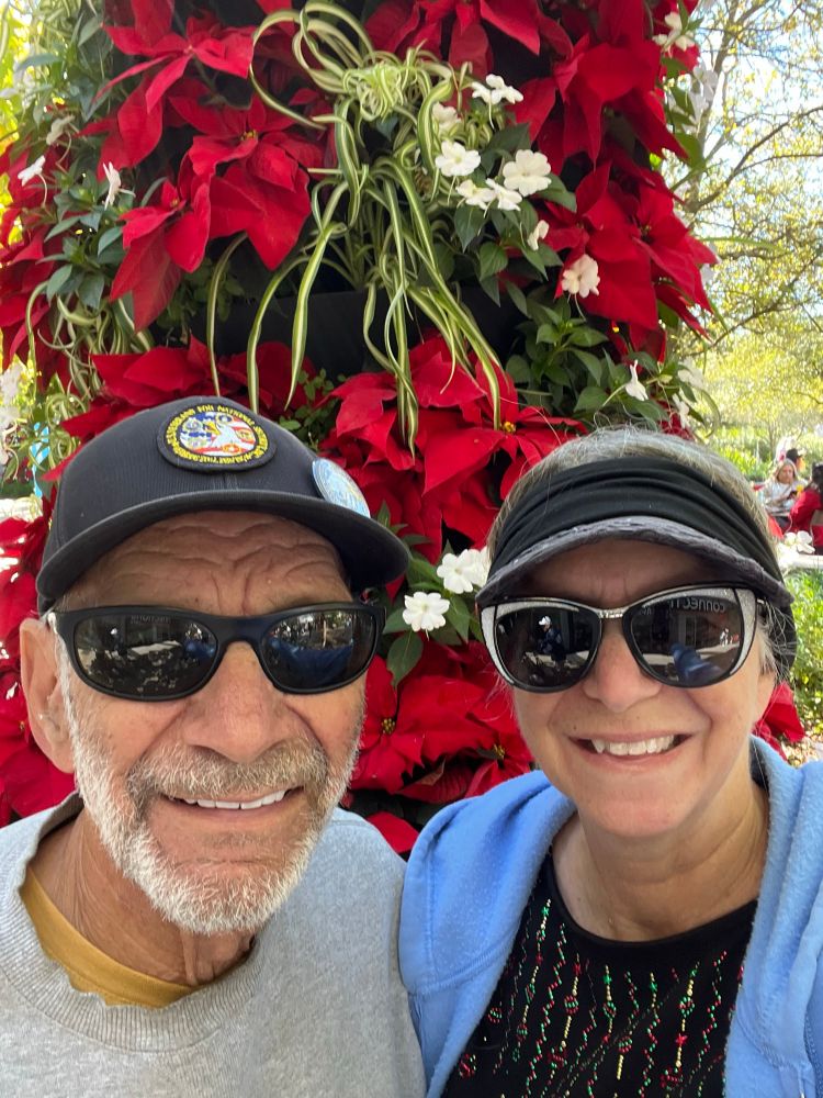 My husband and I standing in front of a tower of poinsettias 