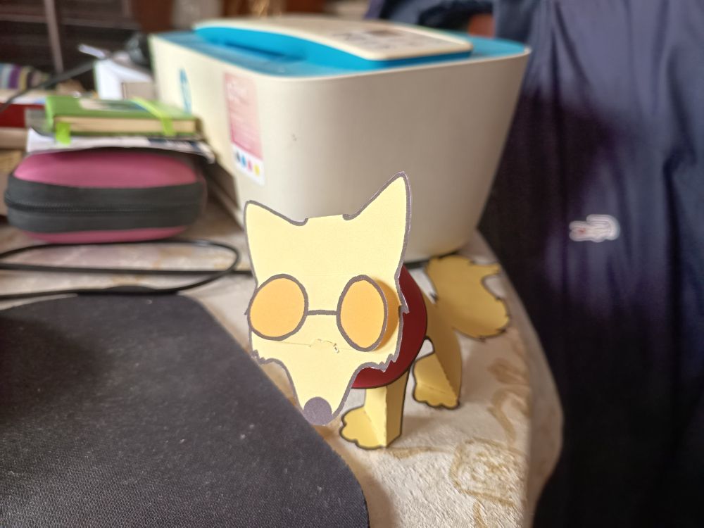 A paper yellow dog with orange glasses red collar and a bushy looking sideways