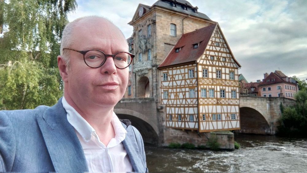 A bald man with glasses standing in front of Bamberg's Old Town Hall