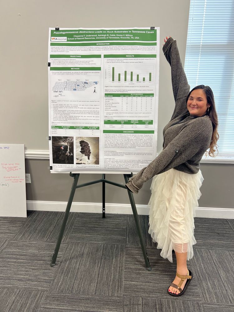 A researcher stands with a research poster