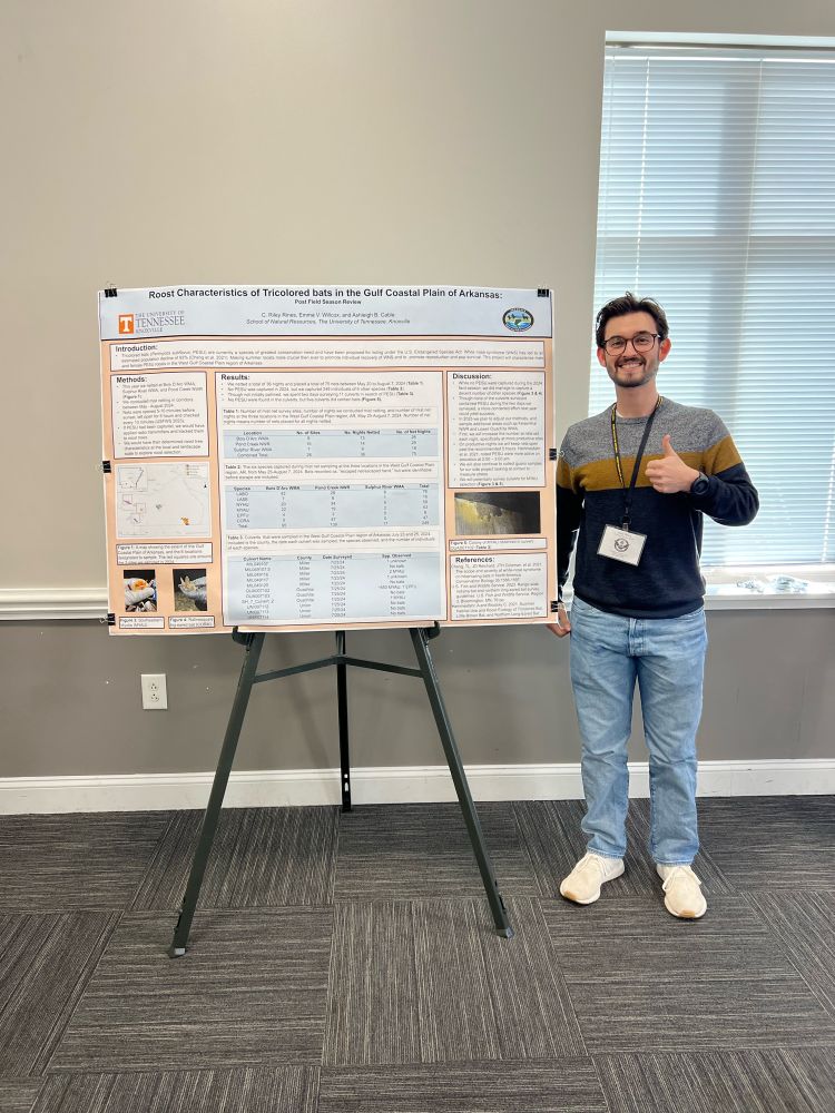 A researcher stands with a research poster