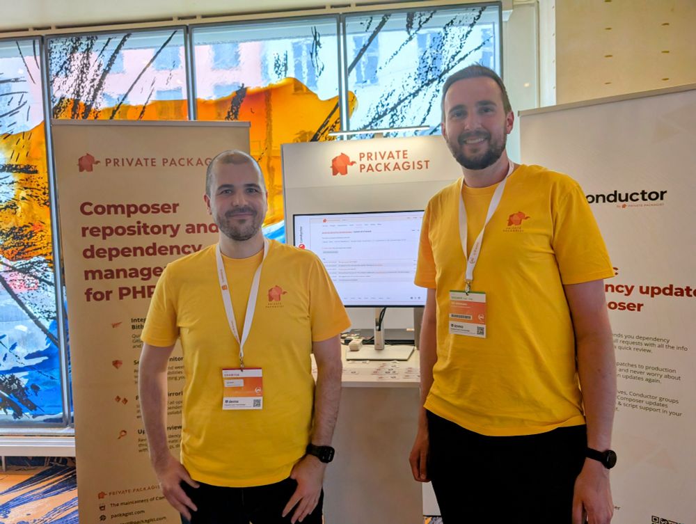 Igor Benko and Nils Adermann in Private Packagist T-shirts in front of a Private Packagist booth