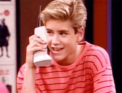 Gif of Zack Morris, Saved By The Bell, on his signature large phone, smiling mischievously 