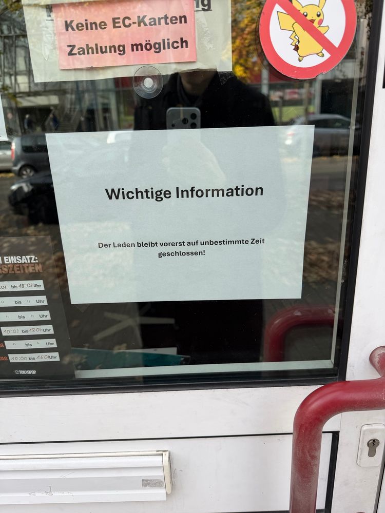 Eine Eingangstür zu einem Geschäft.

Oben links:
Keine EC-Karten
Zahlung möglich

Unten in der Mitte:
Wichtige Information
Der Laden bleibt vorerst auf unbestimmte Zeit geschlossen!

Oben rechts:
Ein durchgestrichenes Pikachu