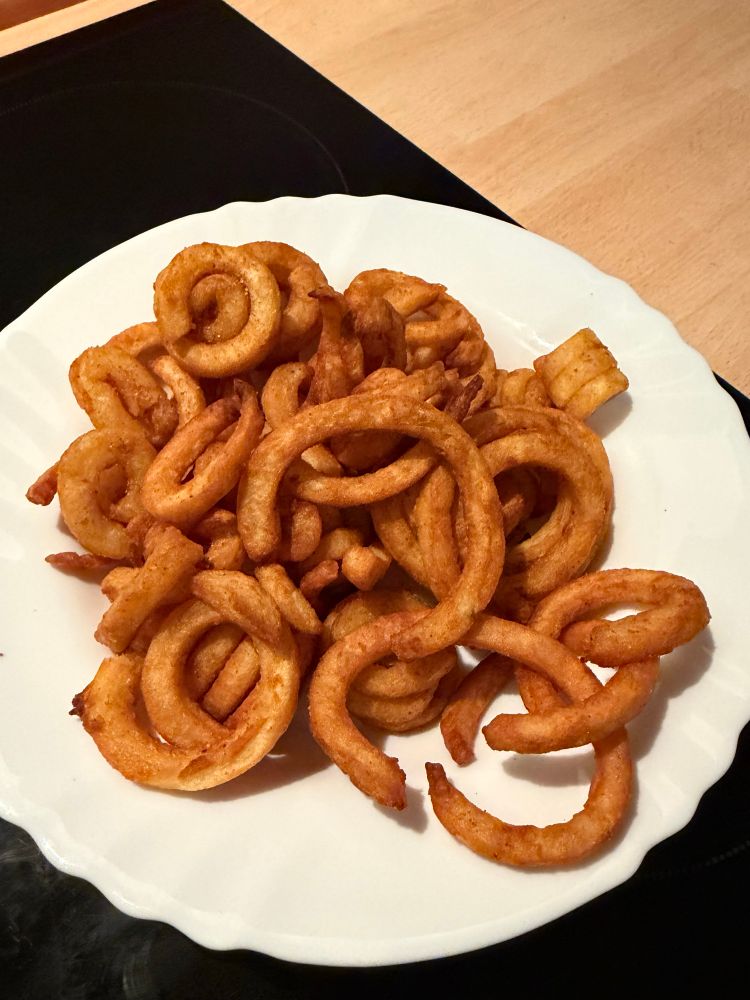 Weißer Teller voller Curly Fries. 