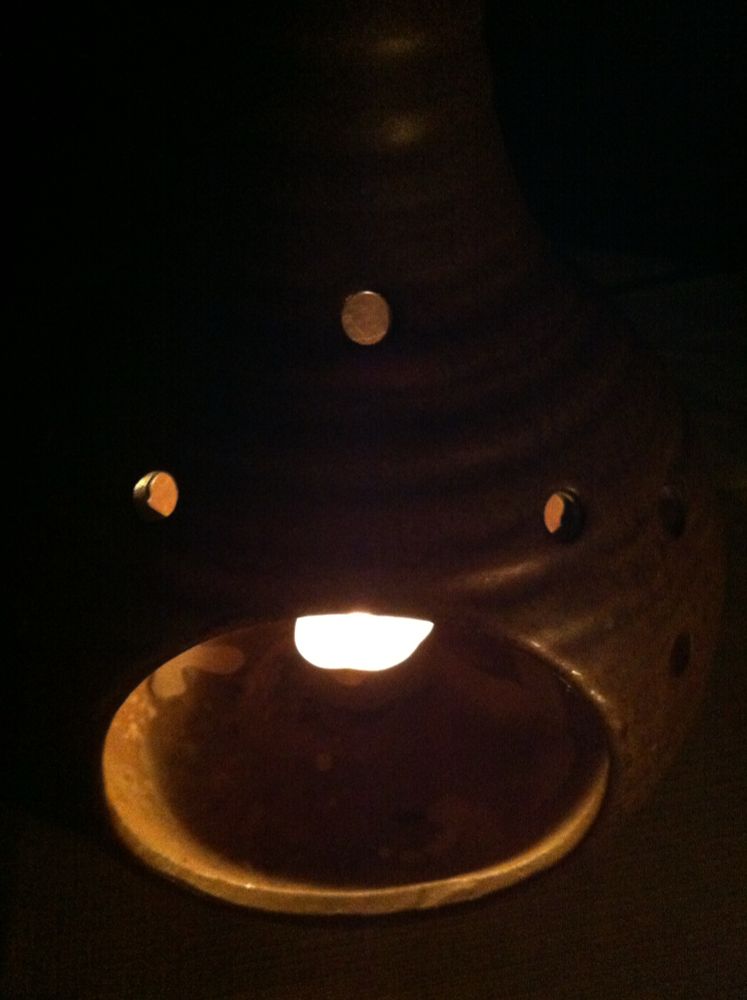 Ein Licht in einer Keramikschale. Der Hintergrund ist dunkel.