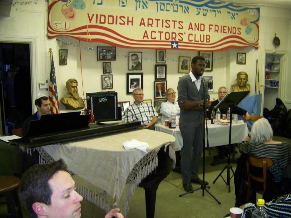 Anthony Russell performing in front a banner emblazoned with the words, "Yiddish Artists and Friends Actors' Club", East Village, 2012