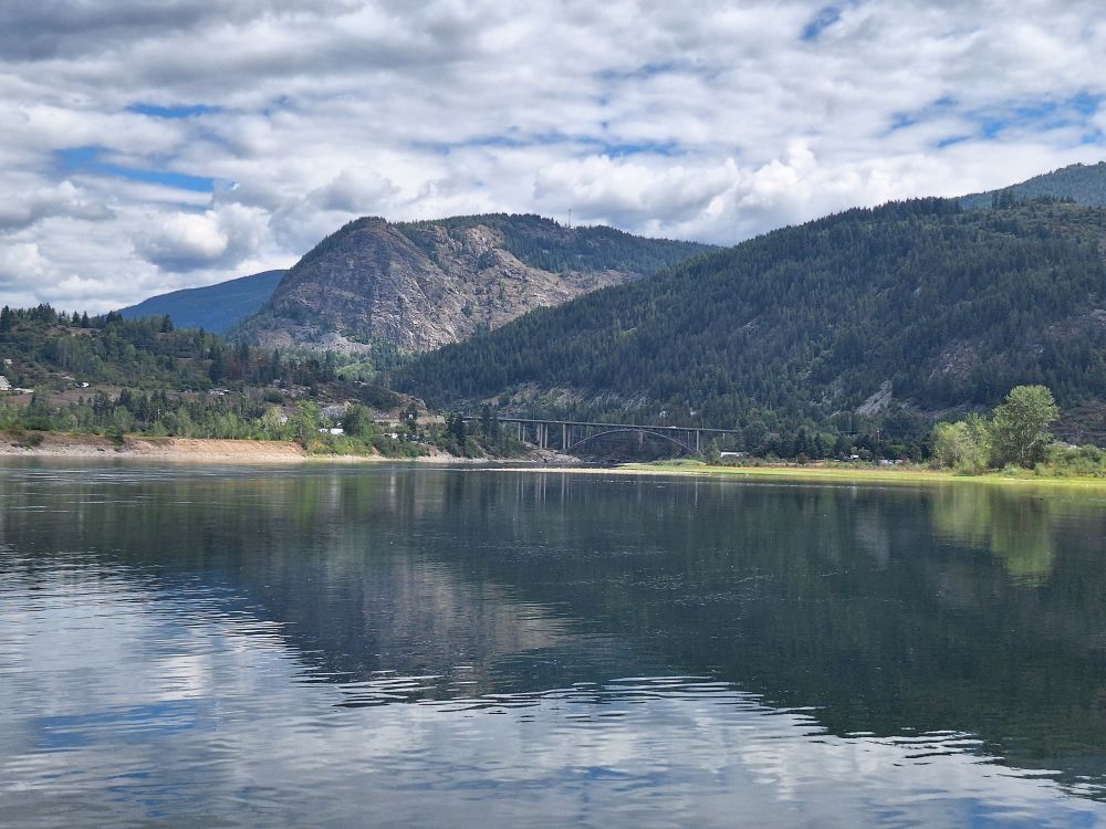 An expanse of water, with mountains and a partly clouded sky in the distance.