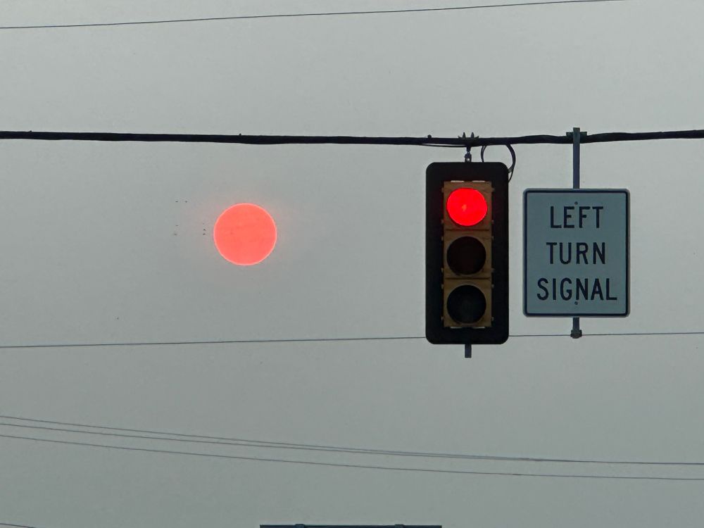 The sun is to the left of a traffic light. The traffic light and sun are both red in color. It looks similar to the Binary Sunset at the end of Star Wars A New Hope. 