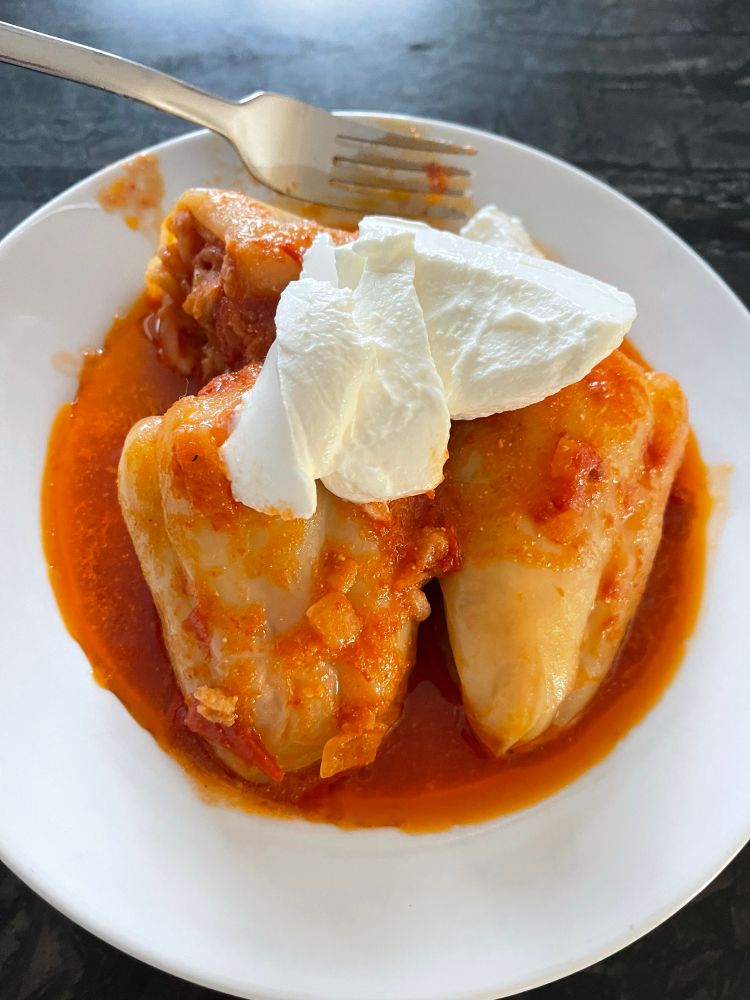 Ukrainian kitchen spotlight: stuffed peppers, served on a simple white plate with a dollop of sour cream on top