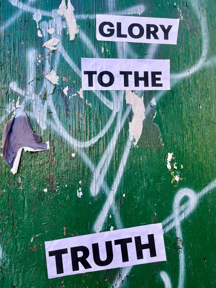 Graffiti on a green wall that says glory to the truth.