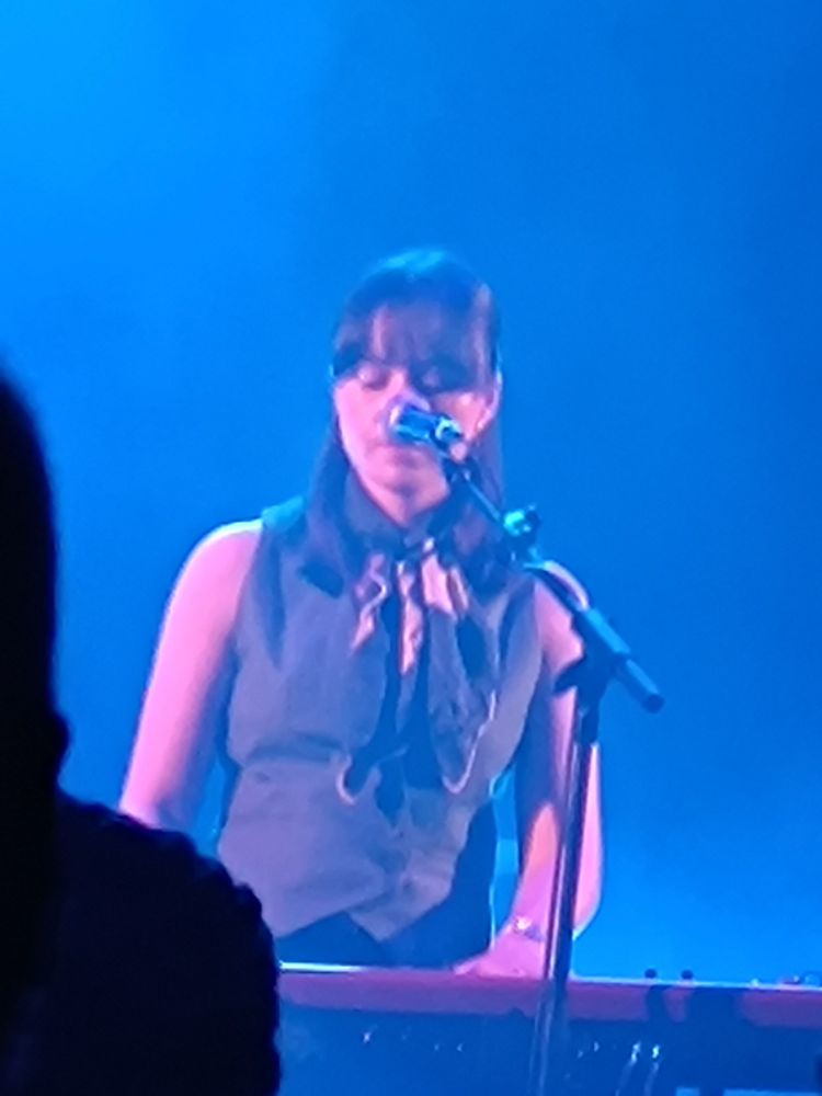 Caoilfhionn Rose playing keyboard and singing, blue ambient light