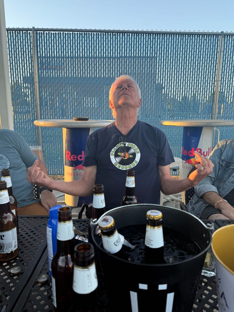 Robert Pollard sitting in front of a bucket of Miller Lites in a modified guru pose