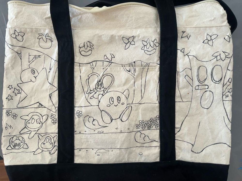 A tote bag with ink drawings depicting a scene with Kirby facing off against a tree boss.