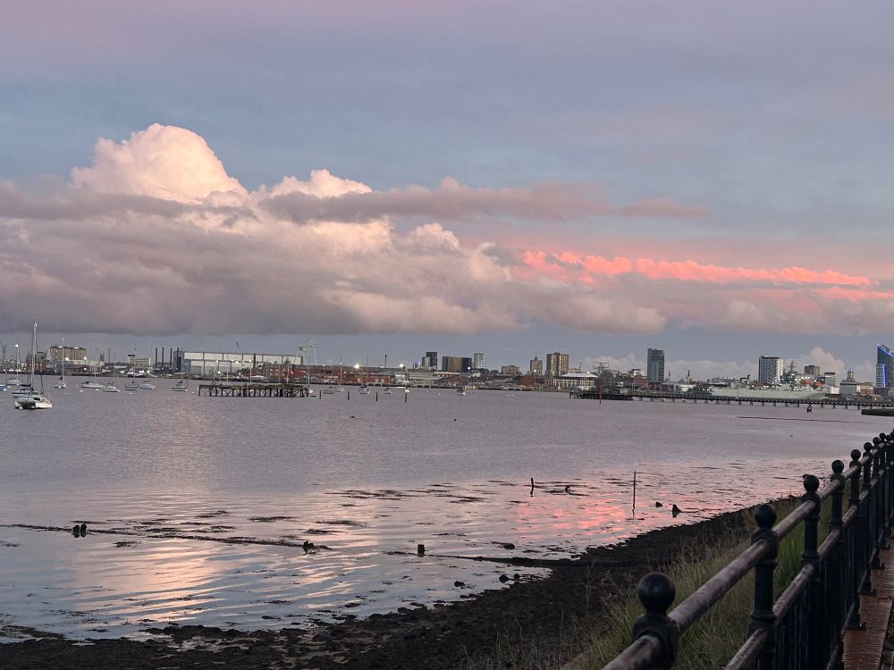 Both white and pinkish clouds reflect in the harbour water 