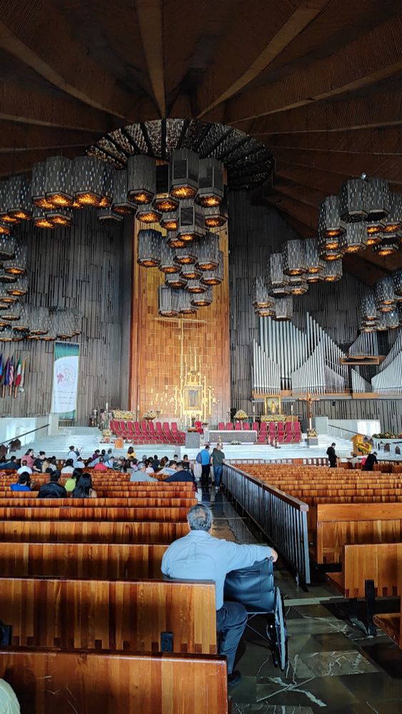Imagem da Basílica da Virgem de Guadalupe, uma igreja com elementos os d madeira, concreto, lustres e elementos geométricos.