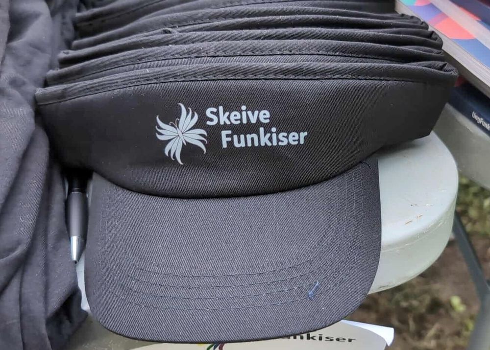 Svart solskjerm med hvitt trykk av vår Skeive Funkiser logo med vår sommerfugl med segmenterte vinger, I hvitt 