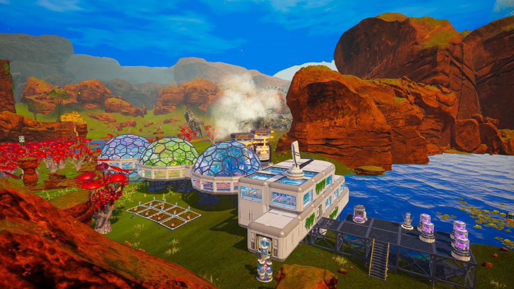 Screenshot from Planet Crafter of an alien planet with brown cliffs, green grass, blue sky and red trees. In the midde by a lake is a base made of several white boxes with rounded edges. Some of them have windows. On the right is a platform with several fusion reactors, and on the left is three domes after each other, the one in the middle is green.