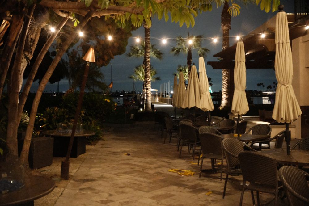 An empty seating area with warm lighting looking out at the water at night