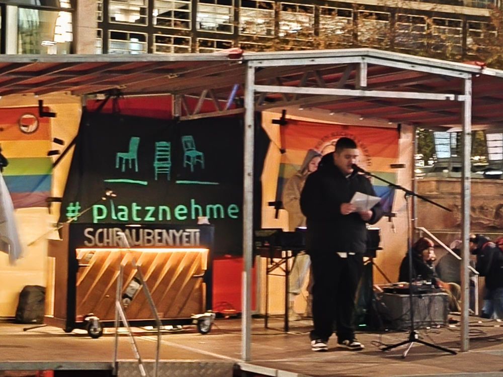 @maxnum.bsky.social auf einer bunten Bühne 