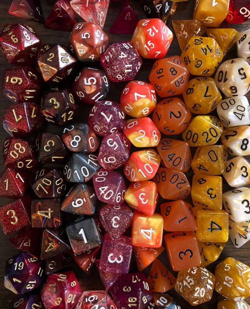a bundle of polyhedral dice in the red to orange to yellow spectrum, arranged in columns and looking really pretty